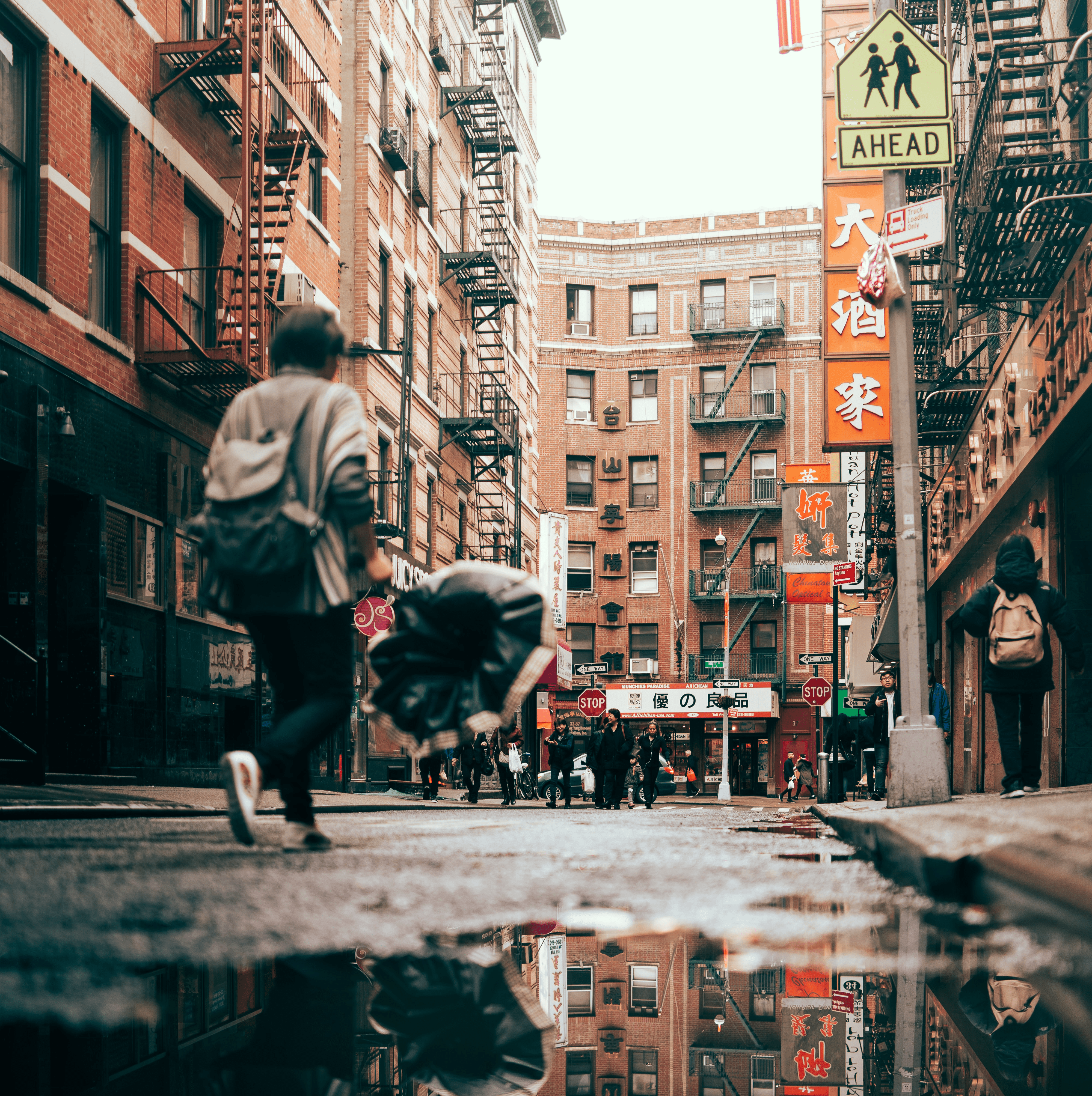 Pedestrians pass signs with English and Chinese characters.