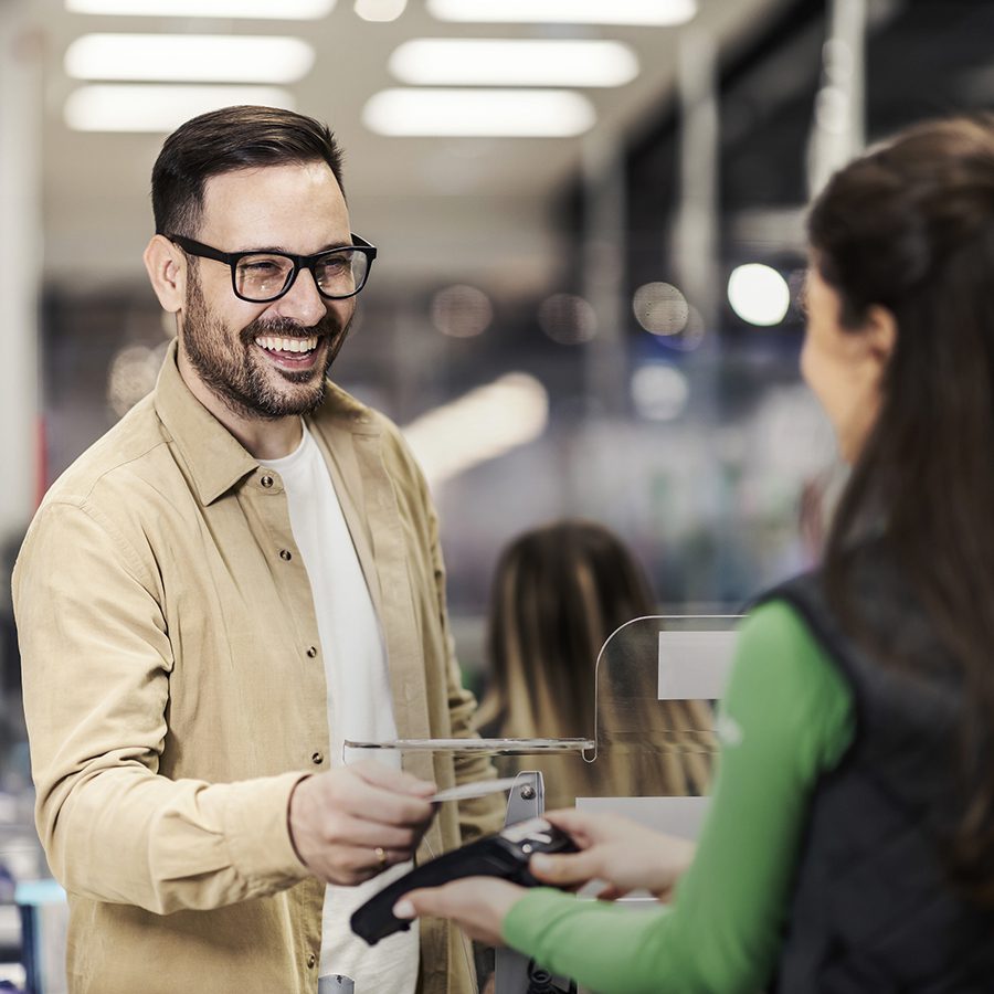 A smiling customer using credit card at checkout, representing Ace Hardware.